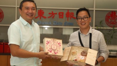 黄思汉（左）赠送新村手工月饼给予《东方日报》，并由中马组助理新闻主任蔡念耀（右）接领。