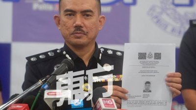 莫哈末再纳手持警方要寻找的华裔男子照片资料，呼吁对方主动现身以助查案件。（摄影：陈启新）
