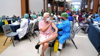 在印尼巴厘省巴东县的一所购物中心，一名医护人员为一名外国男子施打了新冠肺炎苗。（图取自Antara Foto/Fikri Yusuf/路透社）