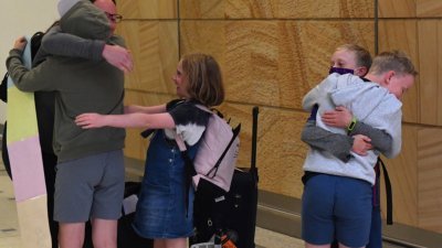 澳洲与纽西兰间的“旅游泡泡”于周一正式开跑。图为来自纽西兰的一家人，在澳洲悉尼机场相拥团聚。-路透社-