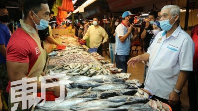 哈山卡林（右）向一名鱼贩了解海产售价。（摄影：刘维杰）