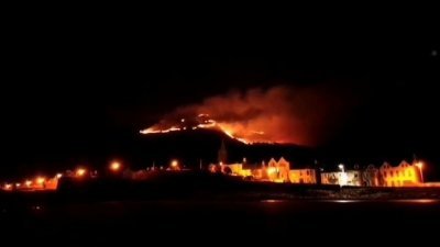 英国北爱尔兰最高山脉莫恩山脉的多纳德山（Slieve Donard）区，当地时间周五凌晨失火，火势延烧至周日，政府派出超过100名消防员灭火。图为莫恩山脉周六持续冒出大火。（图取自推特帐号@MMagiltonSoil/路透社）