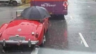鲜红敞篷车司机打著一把黑色雨伞，这幅有趣画面逗乐了不少网民。（取自adminsgfollowsall Instagram）
