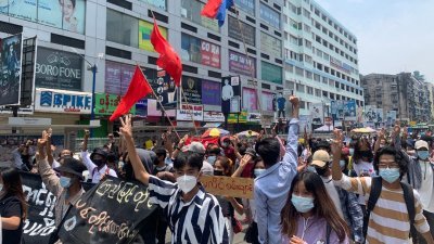 周一在仰光淡汶镇，有反对军事政变的民众上街示威，他们以三指礼表达对极权和独裁者的不满。（图取自法新社）