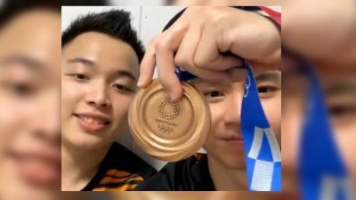 谢定峰（左起）和苏伟译接受电台988越洋直播访问时，兴奋地展示了东奥羽球男双的铜牌。（图片取自988 Instagram）