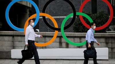 两名上班族周三走过设置在日本桥商业区的奥运五环标志。-路透社-