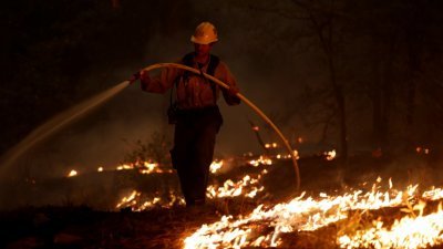 一名消防员上周五晚在格林维尔附近，试图减缓“迪克西山火”蔓延的速度。(图取自路透社)