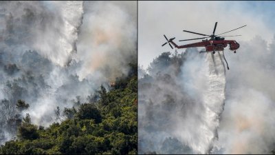 在希腊首都雅典北部马拉卡萨附近的森林，一架直升机当地时间周六从上空投水救火。（法新社）