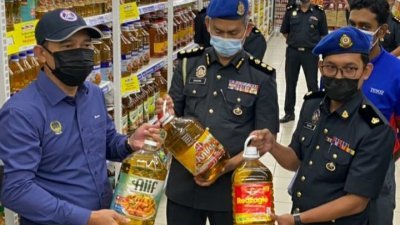 阿都尤努斯（左）在贸消局执法官员陪同下，巡视太平莲花霸市所售卖的食油价格情况，以确保商家遵守条规。