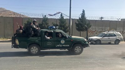 在阿富汗首都喀布尔街头，塔利班武装分子周一开著警车。（图取自路透社）