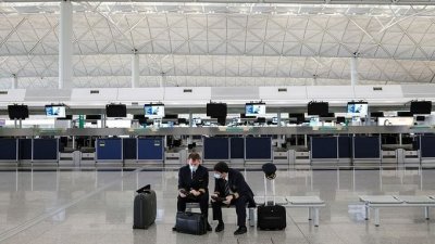 香港特区政府周一公布，收紧包括美国、澳洲、马来西亚、泰国在内的16个海外地区到港人士的检疫要求，周五凌晨12时起生效。图为戴口罩的2名机师在香港国际机场。（路透社档案照）