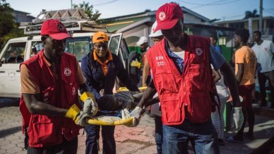 在地震重灾区莱凯市，红十字会护理人员用担架运送一名受伤的女孩到医院接受医治。（图取自路透社）