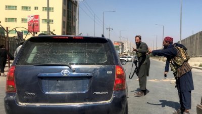 阿富汗武装组织塔利班战士周一在喀布尔街道上，检查来往的车辆。（图取自路透社）