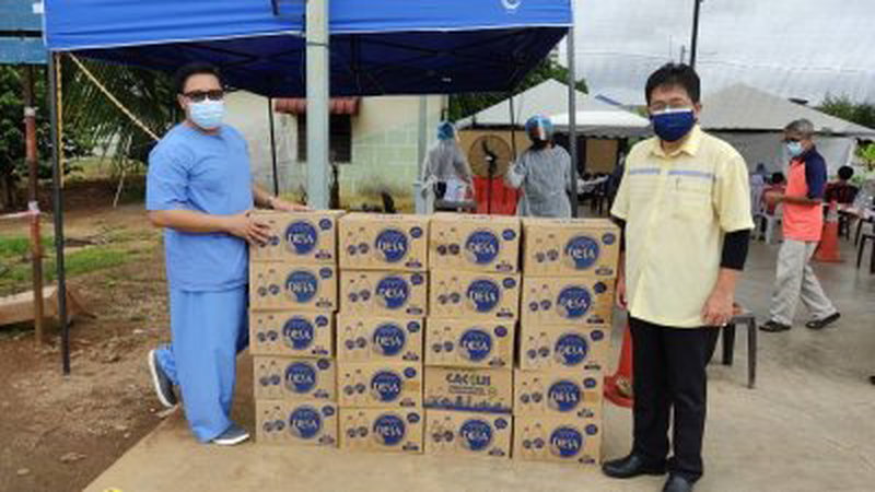 陈正春（右）捐赠矿泉予访昔加末冠病评估中心，了解前线工作人员的工作情况。