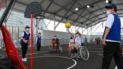 东京残奥会将在周二晚举行开幕式。图为东京残奥会的球迷公园，两名身障人士当天在参与轮椅篮球的活动。（图取自法新社）