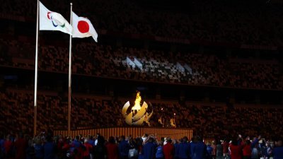 球形的火炬塔开展成花瓣状，圣火由3位火炬手点燃，东道主日本的国旗和残奥会旗帜在一旁的旗杆上飘扬。（图取自路透社）