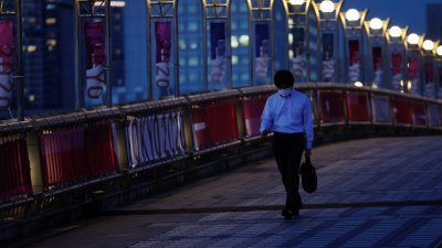 戴著口罩的东京市民，经过梦之大桥上的残奥会宣传横幅。（图取自路透社）