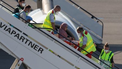 一架载著阿富汗撤离人员的班机于周三，抵达比利时布鲁塞尔的梅尔斯布鲁克军用机场，有人员将行动不便的妇人抬下飞机。-路透社-