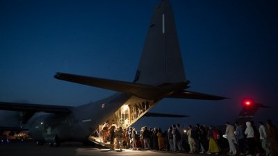 人们在喀布尔机场登上一架法国军用运输机，飞往阿布扎比附近的宰夫拉空军基地，再转往巴黎北部的戴高乐机场。（图取自法新社）