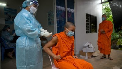 一名少年僧侣周日在金边的一家卫生中心注射科兴疫苗，柬埔寨政府开始为12 至17岁的青少年接种疫苗。（图取自法新社）