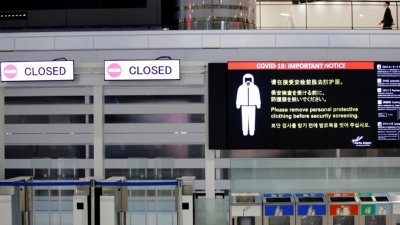 日本在11月30日关闭边界的第一天，成田国际机场出发大厅关闭的门旁边展示了有关新冠肺炎安全措施的通知。（图取自路透社）