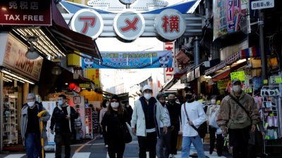 在新冠肺炎疫情爆发期间，戴著防护口罩的行人周三在日本东京的Ameyoko购物区前行。（图取自路透社）