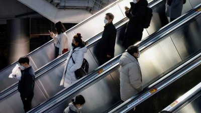 新冠肺炎疫情下，在韩国首尔市的地铁站里，站在手扶电梯的通勤者保持肢体距离。（图取自路透社）