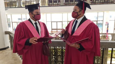 莫哈末祖韩丁（左）和莫哈末祖赫米这对双胞胎一同披上毕业袍，领取大学文凭。