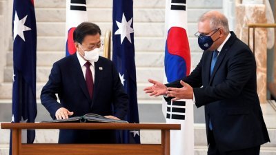 韩国总统文在寅周一造访澳洲国会，并在官方访客登记簿上签名，右为欢迎他的澳洲总理莫里森。