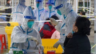 在浙江省宁波市镇海区，在第3轮新冠肺炎病毒大规模检测期间，身著防护服的医务人员周日在核酸检测点采集居民的拭子。（图取自中新社/路透社）