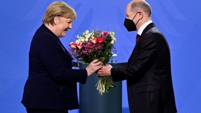 默克尔在12月8日正式卸下德国总理一职，其继任者肖尔茨在当天向她献花。（图取自法新社）