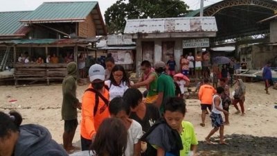 台风登陆前，菲律宾保和省莫卡波克岛的居民，登上木船撤离家园。（图取自路透社/菲律宾海巡署）
