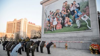 朝鲜人周五在平壤一幅描绘已故最高领导人金日成和金正恩父子的马赛克前鞠躬致敬，以纪念金正日逝世10周年。（图取自法新社）