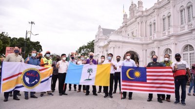 曹观友（前排左4起）与彭文宝等人，拿起国旗、槟城州旗及马来西亚地方政府协会的旗帜，为前往雪州赈灾的人员打气。左起为杨顺兴及尤端祥。（图取自曹观友面子书）