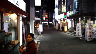 为了预防疫情扩散，韩国政府恢复了防疫限制。图为一家餐厅老板准备在晚上9时开始的宵禁时间前关门。（图取自路透社）