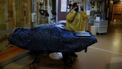 美国因新冠肺炎疫情病殁的人数超越80万人，是全球最多。图为在新墨西哥州的殡仪馆工作人员马丁内斯在运送新冠肺炎死者的尸体前穿上了个人防护装备。（图取自路透社）