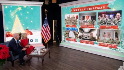美国总统拜登和夫人吉尔，还有他们的新宠物狗于圣诞节当天，在白宫南法院礼堂与军人视讯交谈，感谢他们的服务并祝他们圣诞快乐。（图取自法新社）