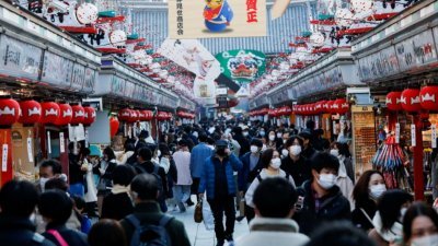 戴著口罩的游客上周五走在东京浅草寺的商业街。（图取自路透社）