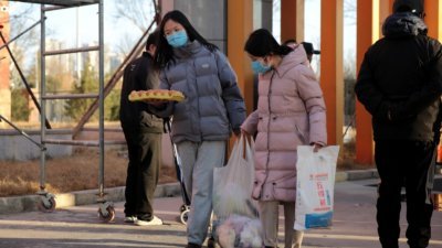 中国陕西省西安市周二晚开始统筹组织发放蔬菜等生活必需品，为封闭管理小区提供物资保障。图为北郊一小区内，居民周三领取到蔬菜等物资。（图取自中新社）