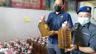 利祖安（左）展示一家工厂涉嫌将津贴食油重新包装成罐装食油，以赚取牟利。