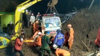 搜救人员用挖泥机吊起因山体滑坡被埋的一辆救护车。（Rescue Motor Indonesia/路透社）