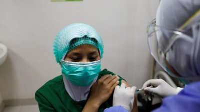 为尽快在贫穷国家中推出新冠肺炎疫苗，世界卫生组织拟在未来几个月内，批准西方国家及中国制造商生产的疫苗。图为医护人员于周四率先在雅加达的一家医院内，接种中国科兴疫苗。（图取自路透社）