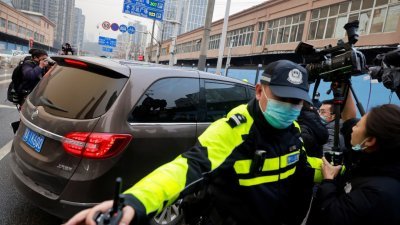 世卫专家组周日下午乘坐车辆直接驶入华南海鲜市场，传媒记者们皆被警察拦住。（路透社）