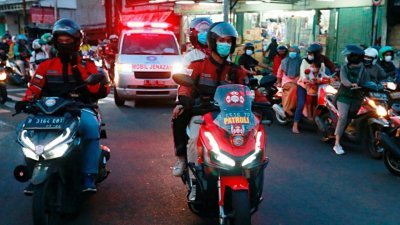 印尼疫情严峻，德波市有一群由志愿者组成的摩哆车队在拥堵的交通中，为救护车开道，以协助他们将新冠患者送往医院或者将病逝者的遗体送到墓园。（图取自路透社）