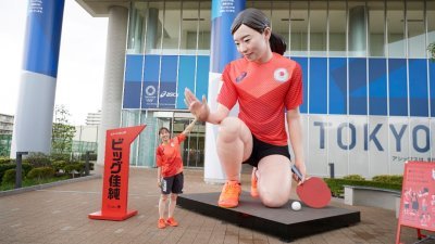 东京奥运会日本代表团副队长的乒乓女将石川佳纯，日前在赞助商Asics为自己打造的巨大雕像前“击掌”拍照打气。（图取自路透社）