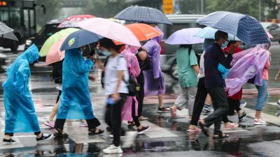 中国首都北京朝阳区团结湖附近，民众周一通过路口。自周日晚上开始，北京迎来入汛以来最强降雨天气。 （图取自中新社）