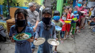 全球去年大约每10个人里就有1人面临食物不足的困境。多家联合国机构周一共同发布的一份报告显示，2020年全球约9.9%的人食物不足，比2019年上升1.5%。图为去年4月10日，印尼西爪哇省万隆市的居民戴著口罩，拿著盘子排队领取免费食物。 （路透社档案照）