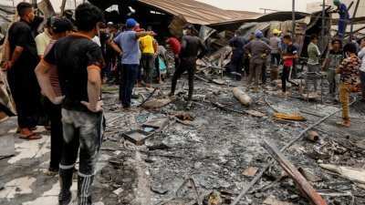 伊拉克济加尔省首府纳西里耶市的侯赛因医院，当地时间周一晚发生火患，死亡人数至今上升至92人。图为民众周二聚集在该事发地点。 （图取自路透社）