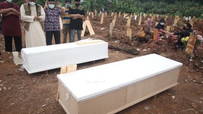 印尼雅加达郊区的南丹格朗病例激增，亡者家属们在政府为病殁者提供的墓地出席葬礼祈祷。(安塔拉通讯社/路透社)