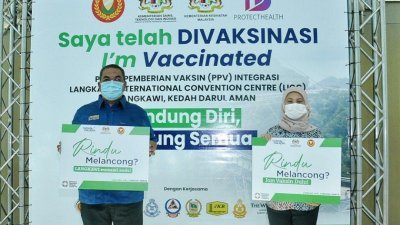 沙努西（左起）及南希苏克里手持旅游部宣传牌，鼓励民众越快施打疫苗，就越快能展开旅游活动。